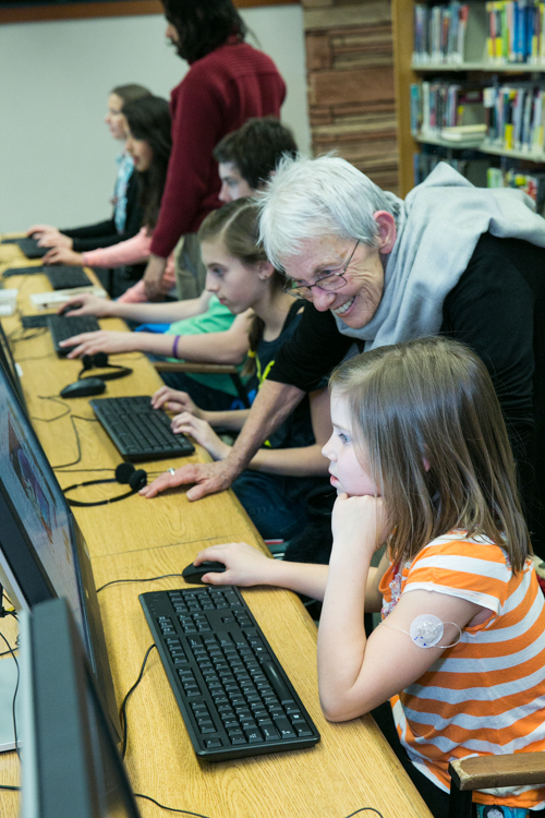 A librarian helps children with computers